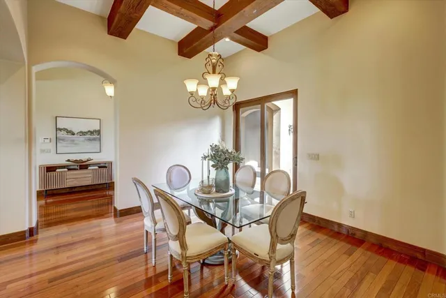 a dining room with wooden floor a chandelier a wooden table and chairs