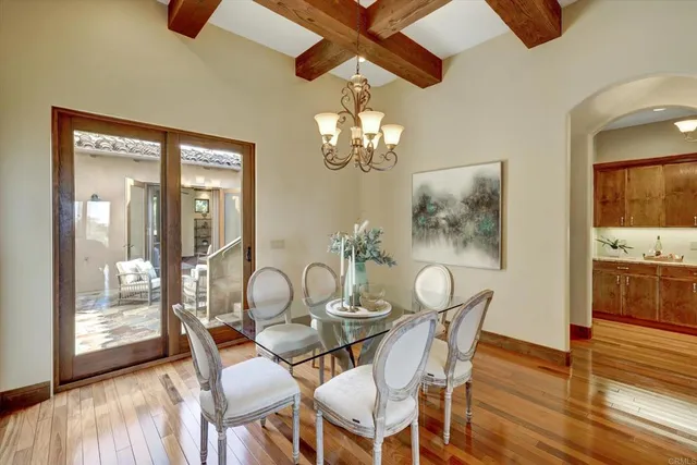 a dining room with wooden floor a chandelier a glass table and chairs