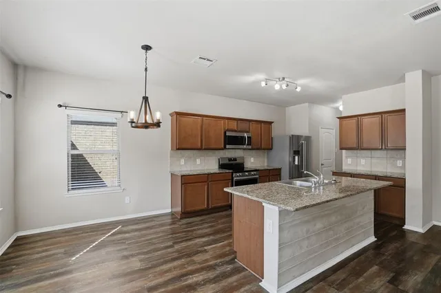 a kitchen with kitchen island granite countertop a sink appliances cabinets and a counter space