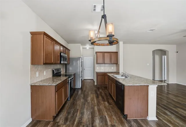 a kitchen with granite countertop a sink stainless steel appliances and cabinets