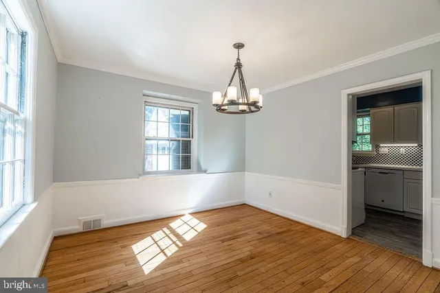 a view of empty room with wooden floor and kitchen view