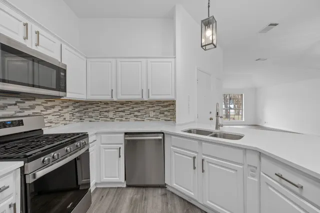 a kitchen with white cabinets and appliances