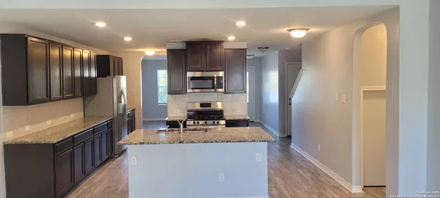 a kitchen with stainless steel appliances granite countertop a refrigerator a stove a sink a microwave oven with a dining table and chairs