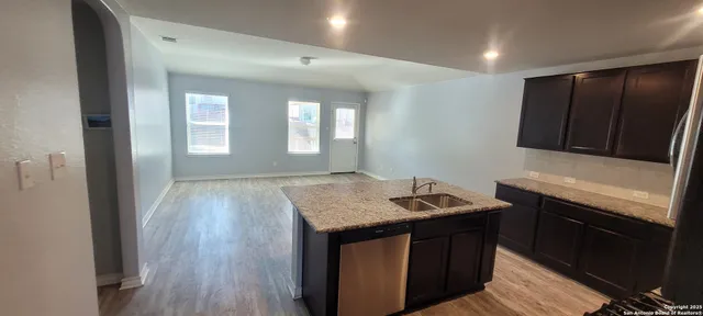 a kitchen that has a sink a microwave oven a stove and white cabinets with wooden floor