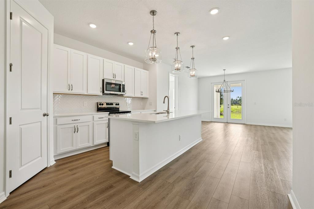 5740 Haystack Drive St. Cloud, FL 34771 - Photo 12 of 39 a large kitchen with cabinets wooden floor and stainless steel appliances