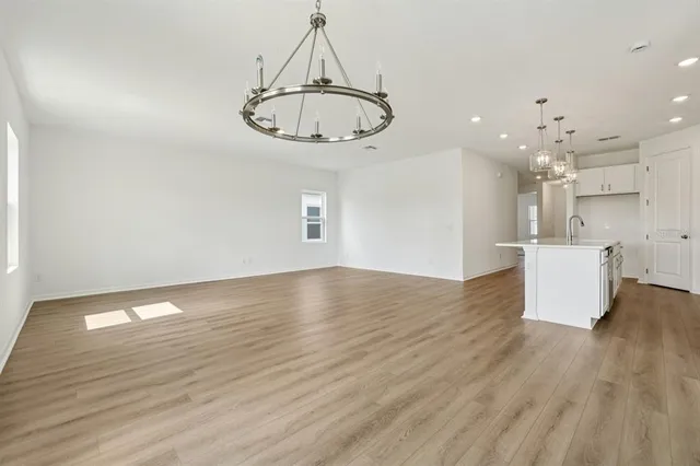 a view of a room with kitchen island stainless steel appliances wooden floor and window