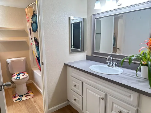 a bathroom with a granite countertop sink a large mirror and a toilet