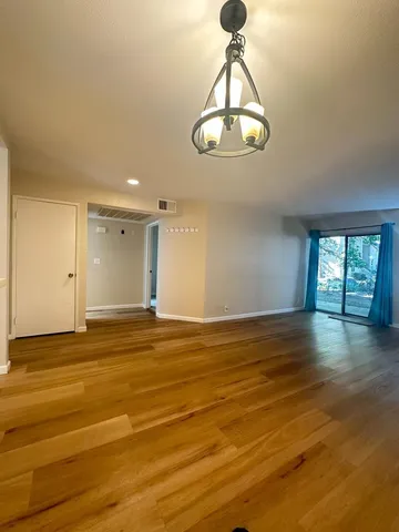 a view of empty room with wooden floor and window