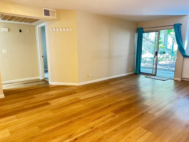 an empty room with wooden floor and windows