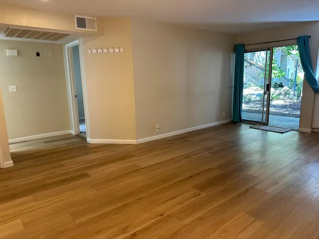a view of an empty room with wooden floor and a window