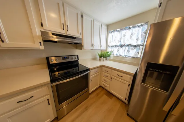 a kitchen with stainless steel appliances wooden floor sink and wooden cabinets