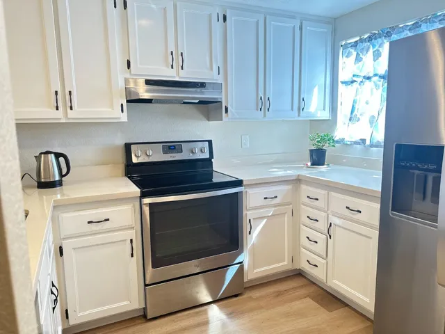 a kitchen with white cabinets and appliances