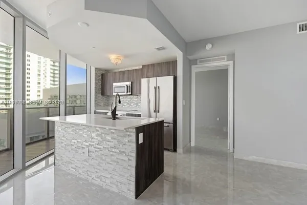 a large kitchen with granite countertop a refrigerator and a stove top oven