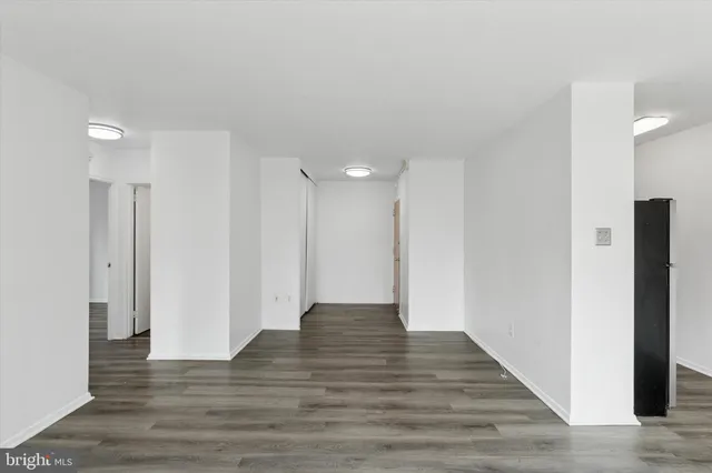 a view of an empty room with wooden floor and a ceiling fan