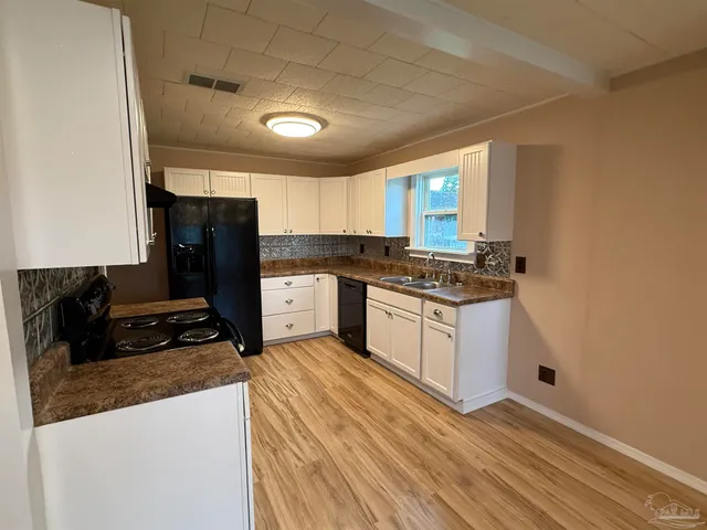 a kitchen with granite countertop a refrigerator stove top oven and sink