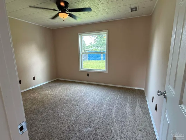 an empty room with windows and fan