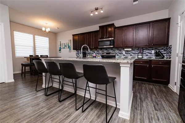 a kitchen with granite countertop wooden floors furniture dining table and stainless steel appliances