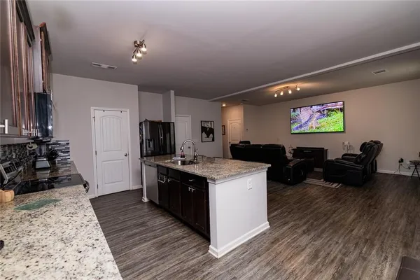 a large kitchen with stainless steel appliances a stove a sink dishwasher and a refrigerator with wooden floor