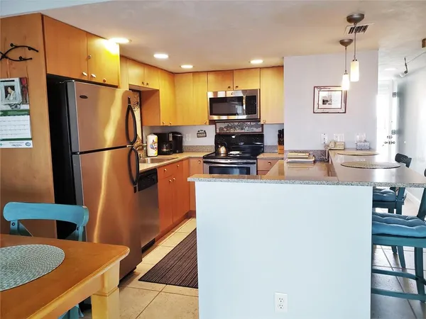 a kitchen with stainless steel appliances a refrigerator a stove a sink a dining table and chairs