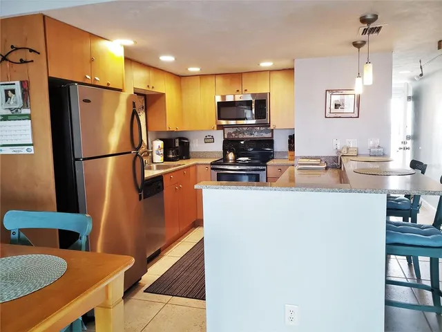 a kitchen with stainless steel appliances a refrigerator a stove a sink a dining table and chairs