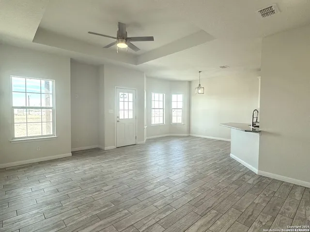 a view of an empty room with a window and wooden floor