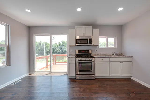 a kitchen with granite countertop a stove a sink and a microwave