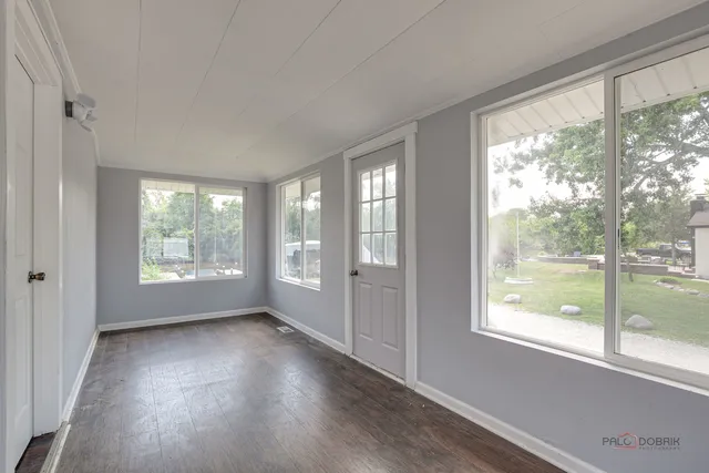 a view of an empty room with glass windows and wooden floor