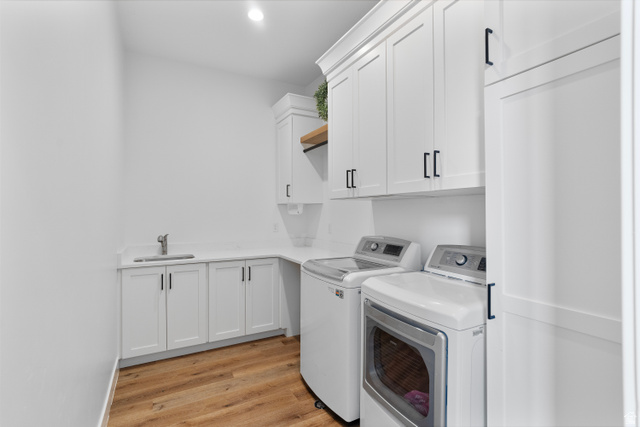 2278 Tawny Ridge Circle St. George, UT 84790 - Photo 19 of 61 Dedicated laundry room featuring wood-finish flooring, white cabinetry with matte black hardware, white countertops, and an integrated utility sink with a stainless steel faucet.