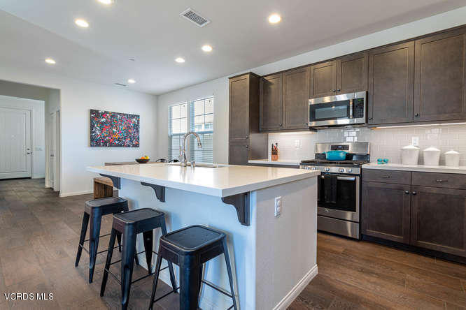 239 Stonegate Road Camarillo, CA 93010 - Photo 4 of 25 a kitchen with stainless steel appliances kitchen island granite countertop a sink and stove top oven with wooden floor