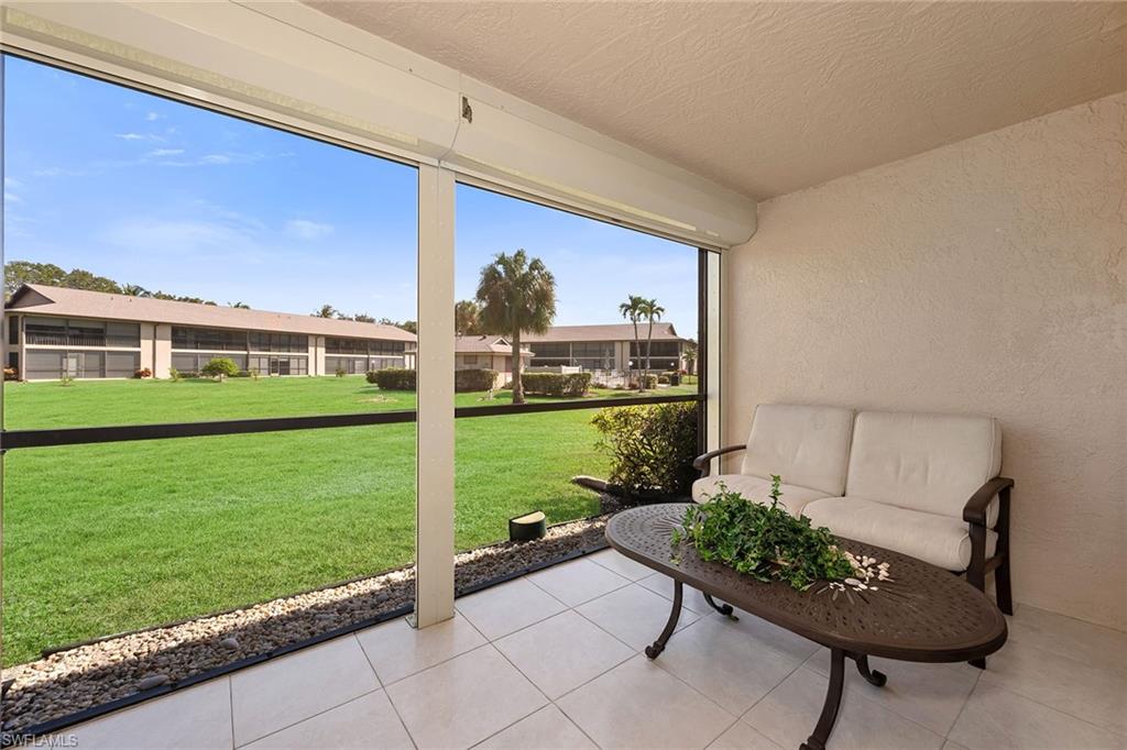 236 Pebble Beach Circle, Unit A102 Naples, FL 34113 - Photo 29 of 40 a view of a chair and tables in the garden