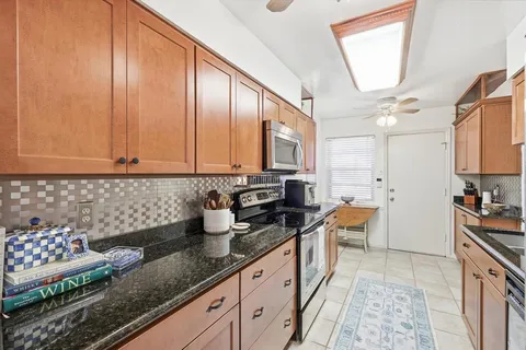 a kitchen with granite countertop a sink a stove and cabinets