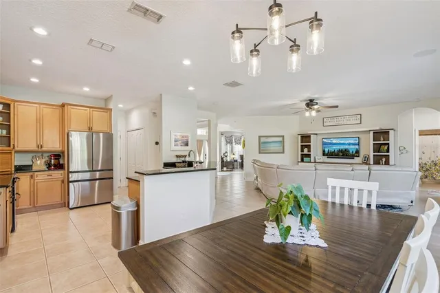 a kitchen with stainless steel appliances granite countertop a refrigerator a stove top oven a dining table and chairs with wooden floor