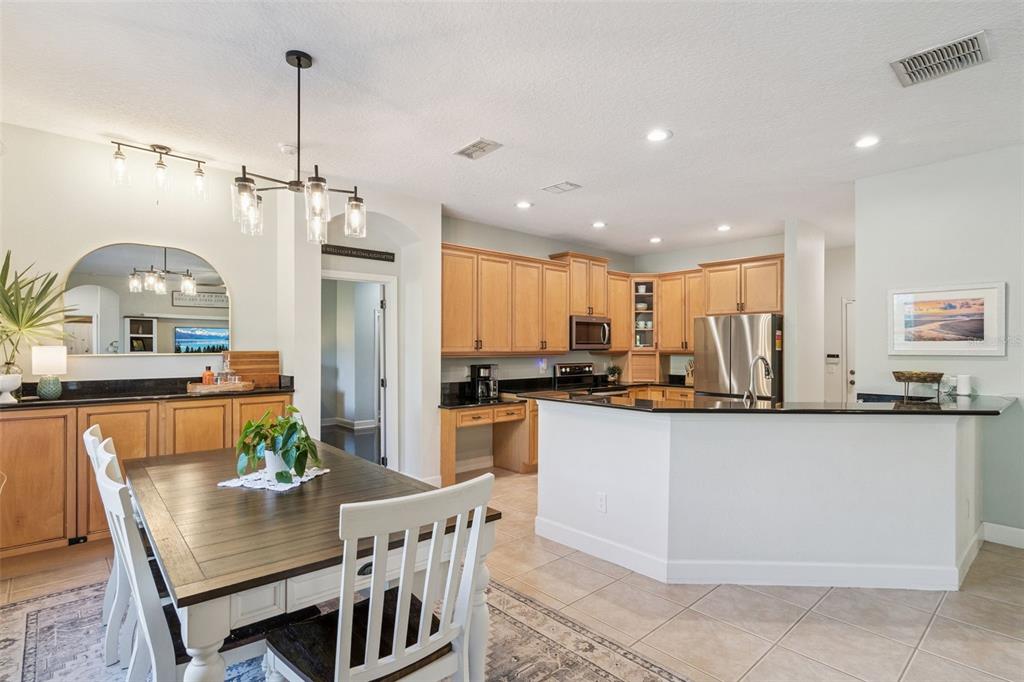1471 Wescott Loop Winter Springs, FL 32708 - Photo 16 of 57 a kitchen with stainless steel appliances granite countertop a refrigerator a sink dishwasher a dining table and chairs with wooden floor