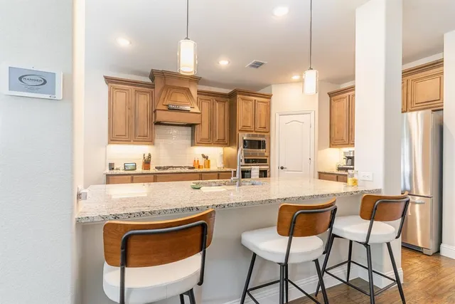 a kitchen with stainless steel appliances a stove a sink dishwasher a refrigerator and cabinets with wooden floor