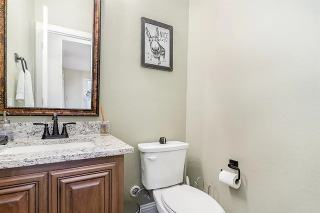 a bathroom with a granite countertop toilet sink and mirror