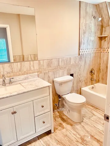 a bathroom with a granite countertop toilet a sink and a bathtub