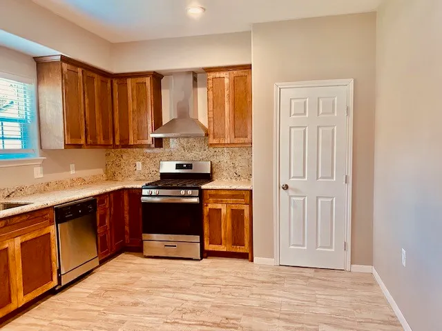 a kitchen with stainless steel appliances granite countertop a stove a sink and a refrigerator with wooden cabinets