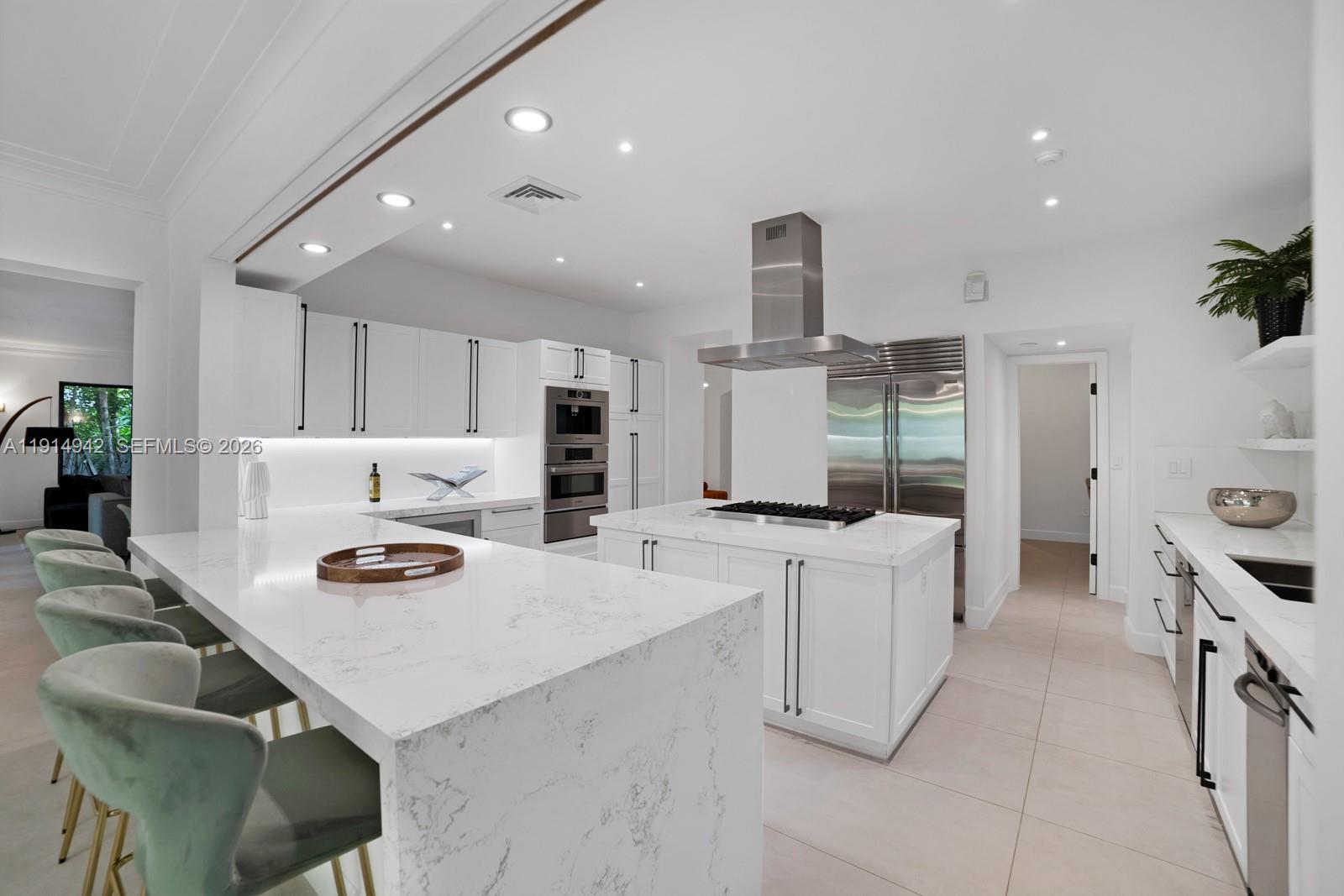 5735 North Bay Road Miami Beach, FL 33140 - Photo 15 of 59 a kitchen with stainless steel appliances a table chairs and a refrigerator