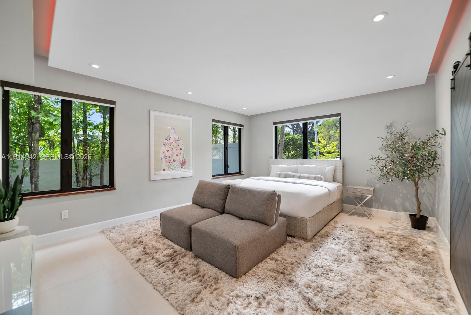 5735 North Bay Road Miami Beach, FL 33140 - Photo 36 of 59 a bedroom with a large bed couch and a large window
