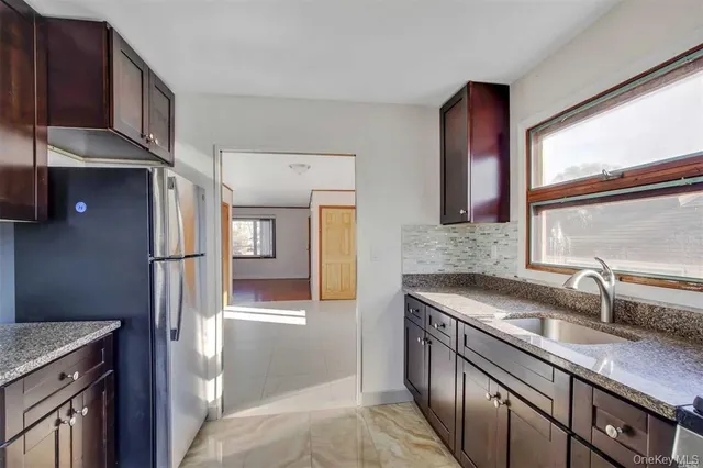 a kitchen with granite countertop a sink and a refrigerator