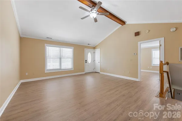 an empty room with wooden floor fan and windows