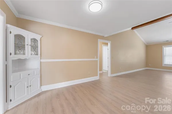 an empty room with wooden floor cabinet and windows