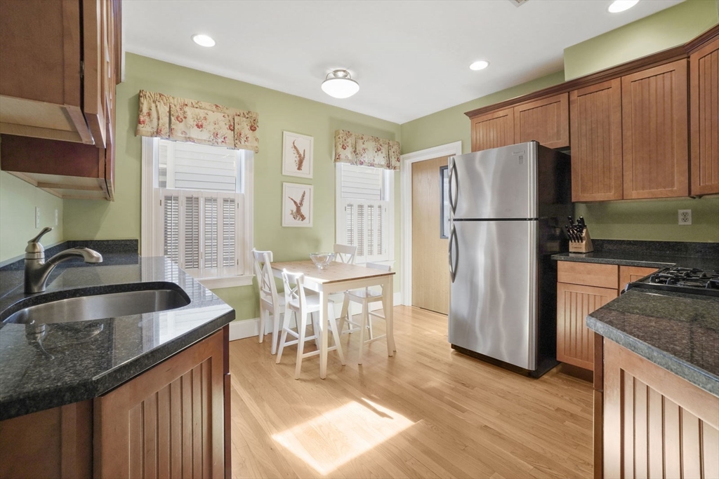 a kitchen with kitchen island granite countertop a refrigerator a sink a stove and wooden cabinets