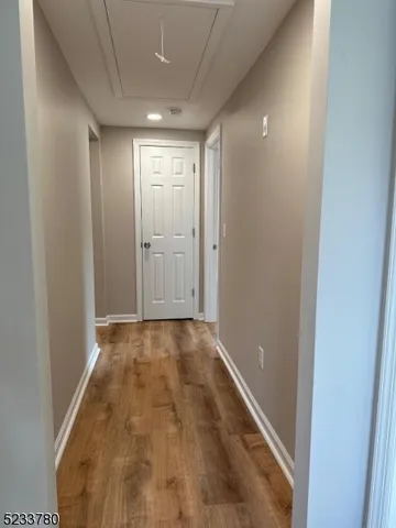 a view of hallway with an empty room and wooden floor