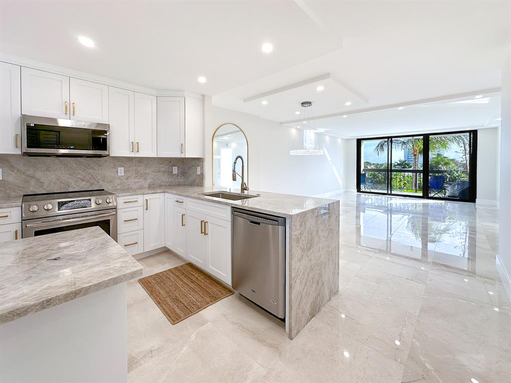 a kitchen with stainless steel appliances granite countertop a stove a sink and a microwave