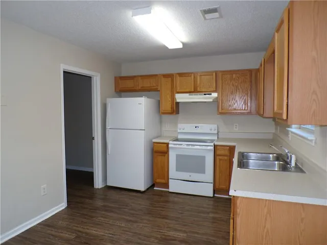 a kitchen with granite countertop wooden floors and white stainless steel appliances