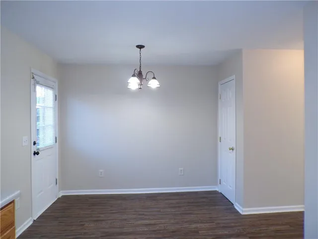 an empty room with wooden floor and chandelier