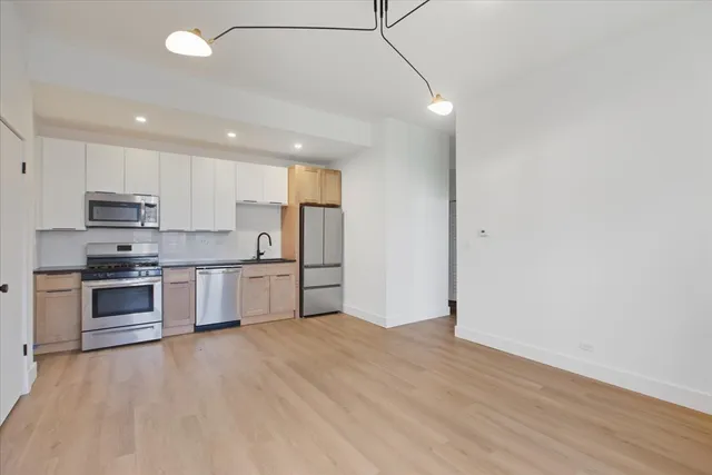 a large kitchen with stainless steel appliances granite countertop a stove a sink and a refrigerator