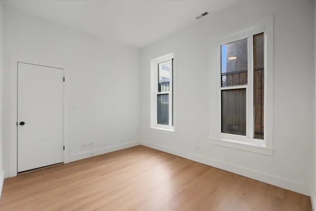 a view of an empty room with wooden floor and windows