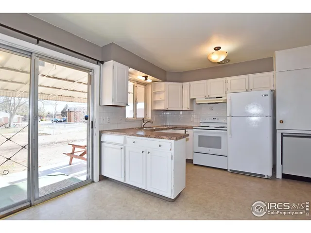 a kitchen with granite countertop white cabinets and white appliances